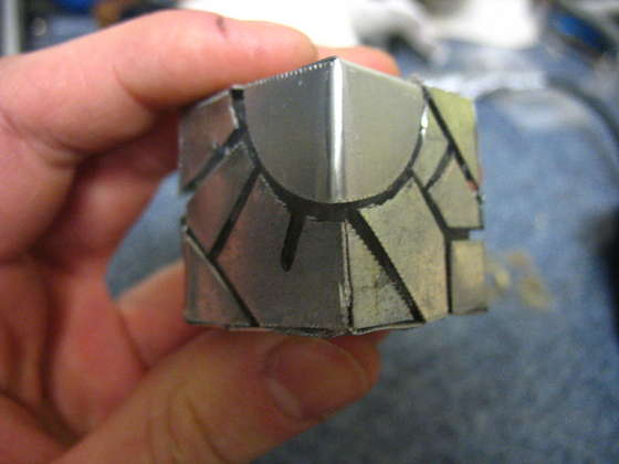 Cut out of the sheet metal futuristic designs and glue them onto the cube. Make sure that when you glue onto the button you don't stop it from being pressed down, and that it sticks out enough to be pushed down.