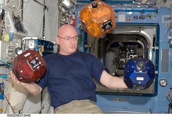 A NASA astronaut with three SPHERES